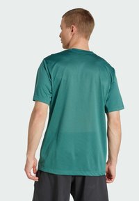T-shirt de sport à manches courtes vert foncé en tissu évacuant l'humidité, avec une coupe décontractée et un motif texturé subtil au dos.