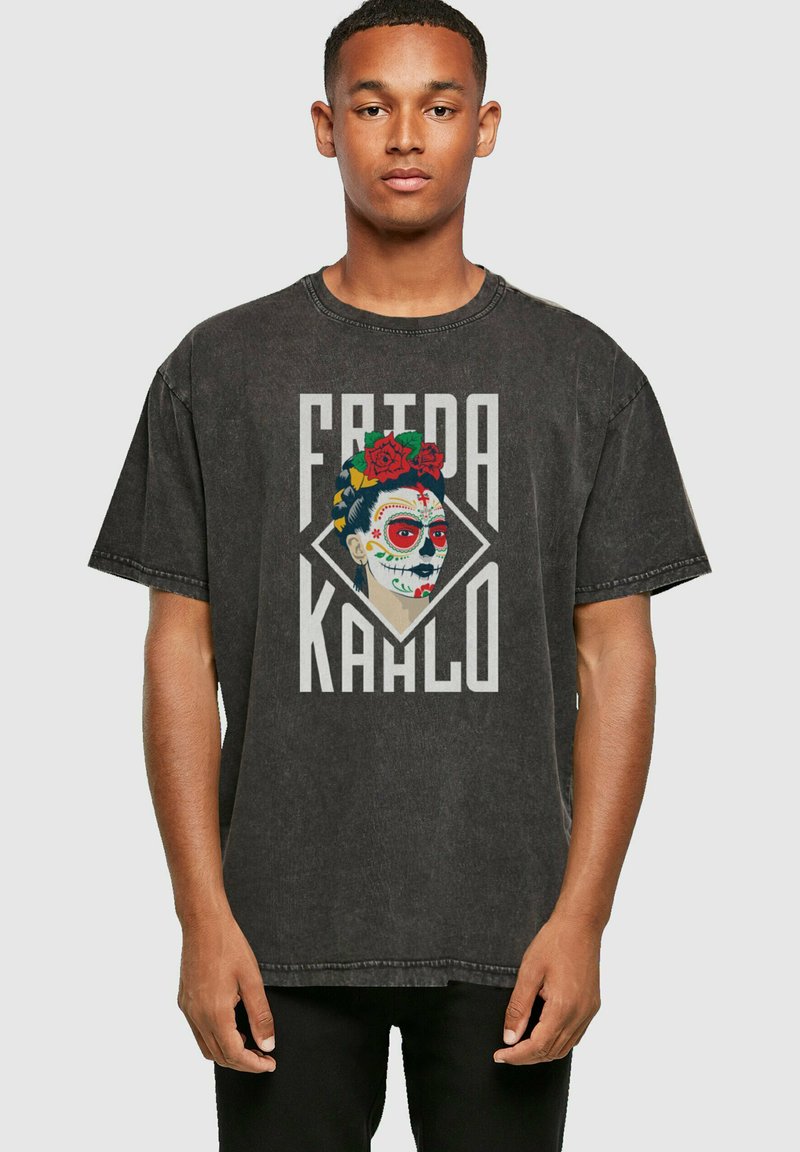 Tumši pelēks pārāk liels T-krekls ar krāsainu Frida Kahlo grafiku, kas papildināta ar ziedu akcentiem un drosmīgu rakstību uz teksturētas auduma.