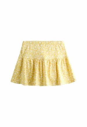 Gul nederdel med hvidt blomsterprint, rynket talje og udvidet flæse-kant, vist på hvid baggrund.