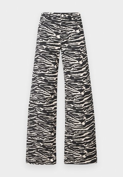 Platas kājas bikses melnbaltā zebras svītru rakstā. Izgatavotas no teksturēta auduma ar klasisku jostasvietu un priekšējiem kabatām.