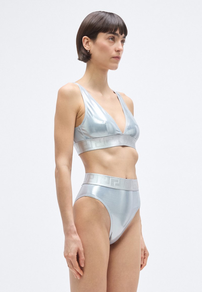 Metalen zilveren lingerie set met een V-hals bralette en hoog uitgesneden slip, met een gestructureerde tailleband en een gladde stofafwerking.