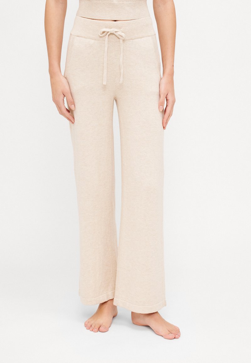 Beige wide-leg pants made of soft fabric, featuring a drawstring waist and ribbed details. Includes two side pockets.