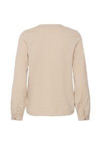 Chemise beige à manches longues avec poignets boutonnés, vue de dos sur fond blanc.