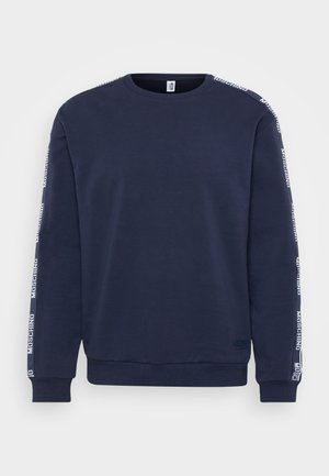 Sweatshirt bleu marine à manches longues, avec des poignets côtelés et du ruban logo Moschino blanc courant le long des épaules et des manches.