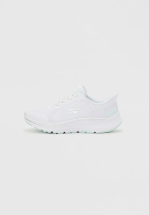 Baskets blanches Skechers pour sport avec tige en mesh, design à lacets, semelle rembourrée et logo de la marque sur le côté, sur un fond uni.