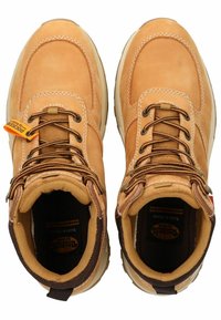 Botas de cuero marrón claro con acentos en marrón, que presentan cordones redondos, un cuello acolchado y una suela de goma texturizada, etiquetadas como resistentes al agua.
