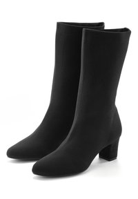 Botas de tobillo negras hechas de un tela texturizada. Presentan una punta afilada y un tacón cuadrado. Diseño liso y ajustado sin herrajes visibles.