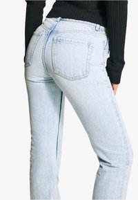 Light blue denim jeans with a straight fit, featuring back pockets and subtle fading. The fabric appears soft with a slightly worn texture.
