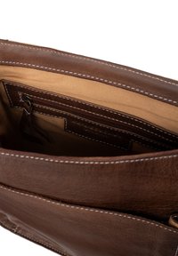 Interiér hnědé kožené kabelky s béžovou textilní podšívkou, obsahující kapsu na zip a několik přihrádek na karty po straně, zdobené bílým prošíváním.