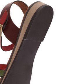 Sandalo in pelle rosso e verde con una suola spessa e testurizzata marrone e un tacco curvo. Cinturino regolabile con dettagli in metallo dorato.