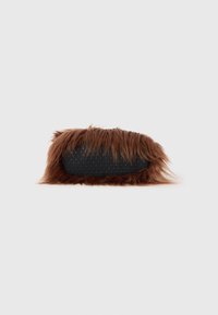 Brun, fluffig toffel med en strukturerad svart sula som har små fördjupningar. Designen är rundad med ett mjukt, plyschliknande utseende.