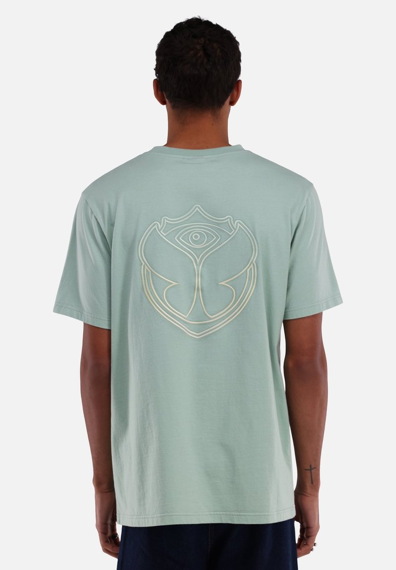 Mintgroen t-shirt, korte mouwen, met een grote witomlijnde grafische ontwerp op de achterkant dat lijkt op een oog binnen een bloemvorm.