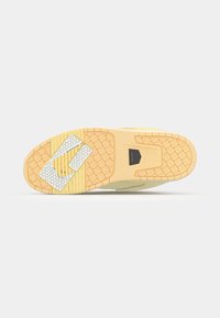 Baskets avec un upper en suède beige, semelle en caoutchouc jaune, motif de semelle hexagonal et un logo en évidement sur la semelle intermédiaire.
