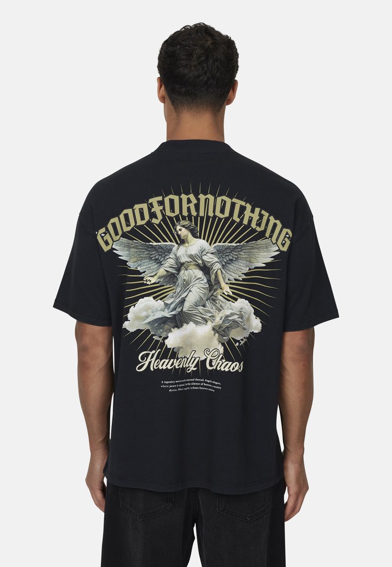 Maglietta nera in cotone con graphic di un angelo alato, dettagli in oro e bianco sul retro, il testo recita "GOODFORNOTHING" e "Heavenly Chaos."
