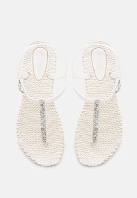 White sandals with a braided texture, adjustable straps, and a decorative rhinestone accent along the center.