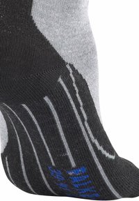 Närbild av en svart och grå sportstrumpa med vita ränder och blå text på sidan, som bärs på en fot mot en vit bakgrund.