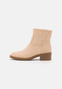 Béžová kotníková bota vyrobená z semiše, s čtveratou špičkou, nízkým odkrytým podpatkem a prošívanými akcenty po stranách. Hladký povrch po celém obvodu.