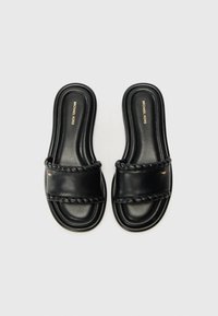 Black leather slide sandals with a twisted strap design, featuring a smooth texture and a gold logo detail on the upper.