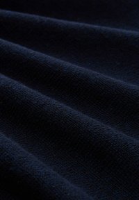 Marineblauer strukturierter Stoff mit wellenförmigen Falten, der ein weiches, gestricktes Aussehen zeigt. Keine sichtbaren Muster oder Hardware-Details.