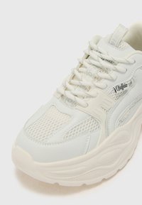 Chunky white sneakers featuring a mix of leather and mesh materials, textured panels, and prominent branding on the side.