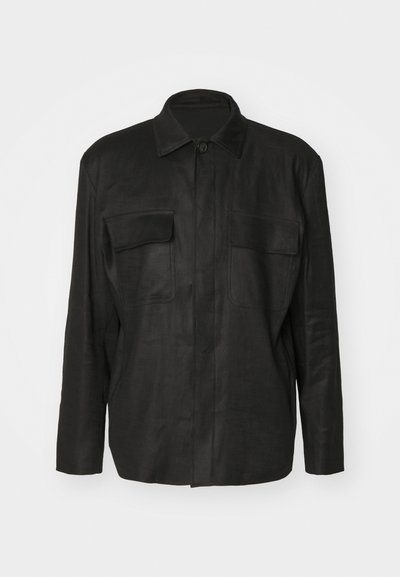 Μαύρο σακάκι φτιαγμένο από λείο ύφασμα, με κλασικό γιακά, μακριά μανίκια, δύο τσέπες στο στήθος και κουμπί στο μπροστινό μέρος.