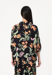 Schwarze Bluse mit floralen Motiven in lebhaftem Orange und Grün, lockerer Schnitt mit kurzen Ärmeln und Kragen, aus leichtem Stoff gefertigt.