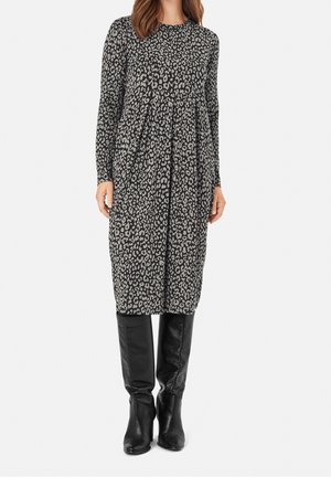 Sukienka z długim rękawem w szary wzór leopardzi, z plisowanym designem, zestawiona z czarnymi kozakami za kolano, tworząc kompletną stylizację.