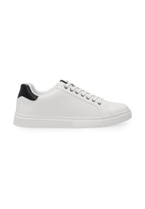 Hvid sneaker med en tekstureret overflade, sort detalje ved hælen, rund tå og klassisk snørelukning. Fleksibel gummisål.