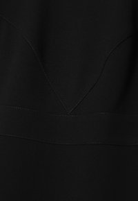 Robe noire avec une coupe ajustée, un tissu texturé, des coutures accentuées et un décolleté en V. Lignes épurées et détails minimaux.