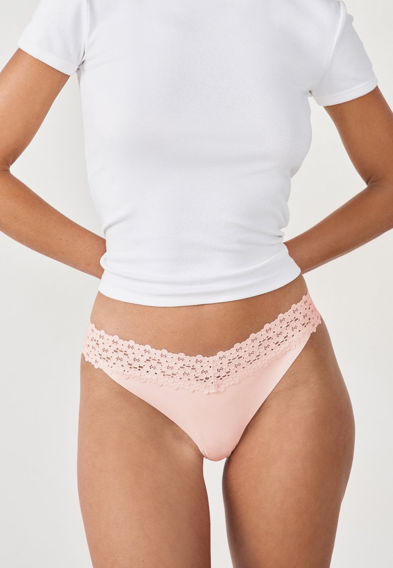 Un string rose avec une délicate ceinture en dentelle. Le matériau semble lisse avec un éclat modéré, contrastant avec la dentelle texturée.