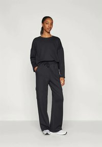 Black casual outfit featuring a loose-fitting long-sleeve top and cargo pants, both made of soft fabric, with pockets and a drawstring waist.