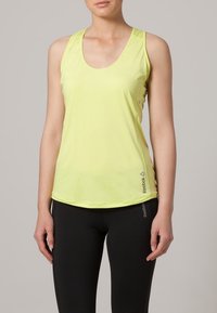 Ljusgul, ärmlös sporttopp tillverkad av mjuk, andningsbar tyg. Har en rund halsringning och diskret logotyp på sidan.
