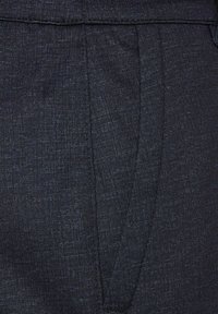 Tessuto grigio scuro con una fine trama, caratterizzato da modelli sottili. Include un frontale piatto e tasche laterali, vestibilità su misura con pieghe nette.