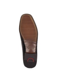 Schwarze geflochtene Leder-Sohle mit einem braunen Gummigriffbereich und einem kreisförmigen roten Akzent nahe der Ferse. Strukturierte Oberfläche für besseren Halt.