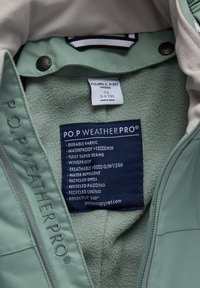 Groene waterdichte jas van duurzaam materiaal, volledig getapete naden, fleece voering en een reflecterend label met verzorginstructies.