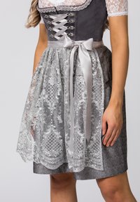 Traditionelles Kleid mit grauem Mieder, silbernem Satinband und transparentem Spitzenüberzug mit floralen Mustern in Grau und Weiß.