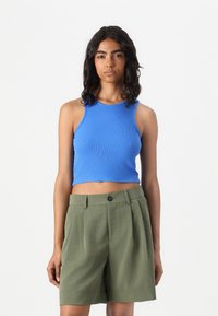 Blue ribbed crop top with a round neckline and sleeveless design, paired with olive green pleated shorts featuring a front button closure.