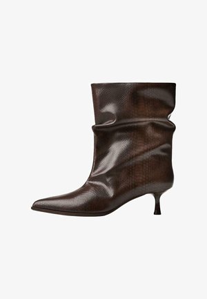 Ciemnobrązowe skórzane botki do kostki z ostrym czubkiem, luźnym cholewem i cienkim niskim obcasem w stylu kociego łapka.
