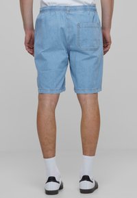 Lyseblå denimshorts med elastisk midje, baklomme og rå kant, med en myk tekstur og uformell passform.