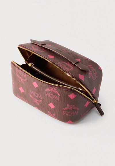Trousse de toilette en cuir marron et rose avec logos MCM, fermeture éclair ouverte sur le dessus et intérieur spacieux visible.