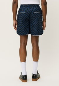 Shorts de culoare bleumarin, cu un model geometric, având un elastic la talie, două buzunare la spate și o margine albă contrastantă.