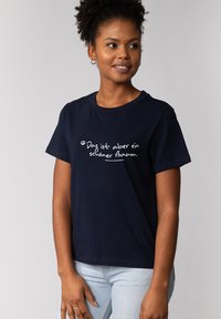 Marineblaue Baumwoll-T-Shirt mit kurzen Ärmeln, mit weißem handgeschriebenem Text "Das ist aber ein schöner Baum" auf der Vorderseite.