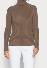 Brauner gerippter Rollkragenpullover mit langen Ärmeln und taillierter Silhouette, aus weichem Material gefertigt. Weiße Hosen passen gut zum Oberteil.