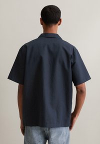 Marineblauwe overhemd met korte mouwen en kraag, gemaakt van een textuurstof, met een ontspannen pasvorm en een nette rugontwerp.