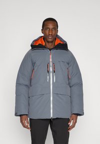 Pánská péřová bunda šedé barvy s oranžovou vnitřní podšívkou. Má kapuci, přední zip, dvě náprsní kapsy a kontrastní zipy.