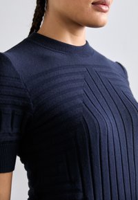 Suéter de punto azul marino con un patr�ón texturizado de rayas en relieve y lisas, mangas cortas y un cuello redondo.