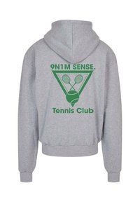 Pelēks kapuce, kurai aizmugurē ir zaļš prints ar trīsstūra dizainu, kurā ir krustoti tenisa raketi un teksts "9N1M SENSE. Tenisa klubs".