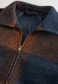 Wool zip-up jacket in a plaid pattern featuring warm brown and blue hues, sturdy zipper, and a smooth inner lining.