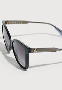 Ochelari de soare pătrați negri cu lentile întunecate și brațe gri cu model, având un mic logo decorativ auriu pe lateral.