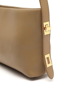 Borsa a mano in pelle beige con una texture liscia; presenta una chiusura in metallo color oro e dettagli cuciti lungo la tracolla.
